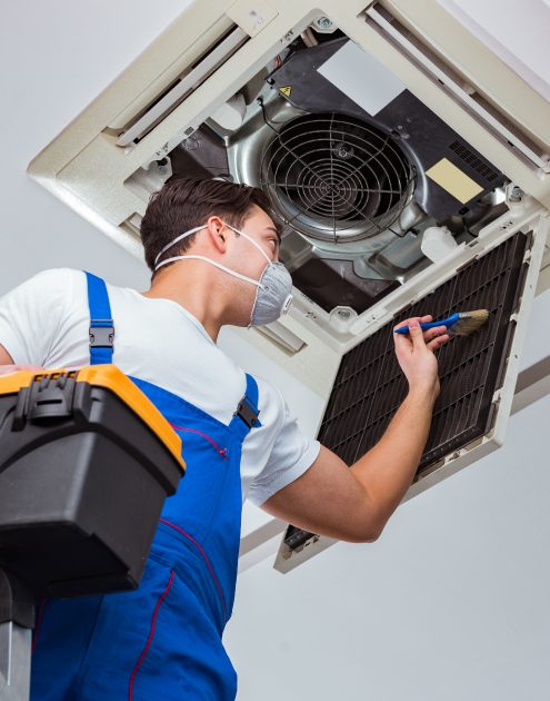 Worker repairing ceiling air conditioning unit